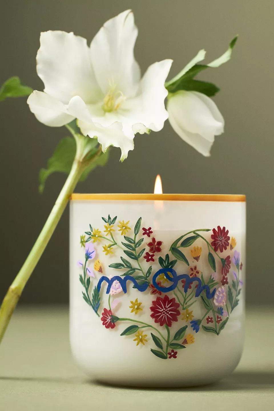 A candle in a floral glass jar