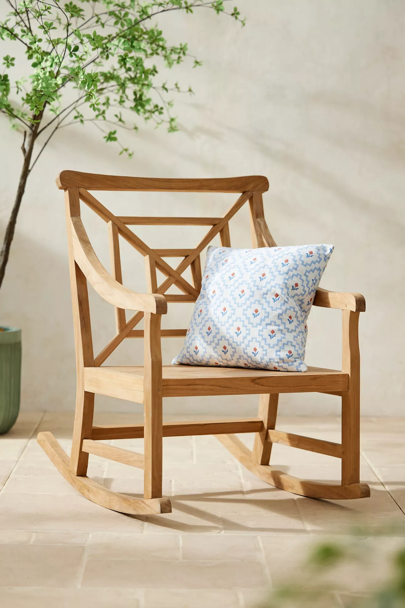 Three-quarter view of teak fretwork rocking chair with pillow