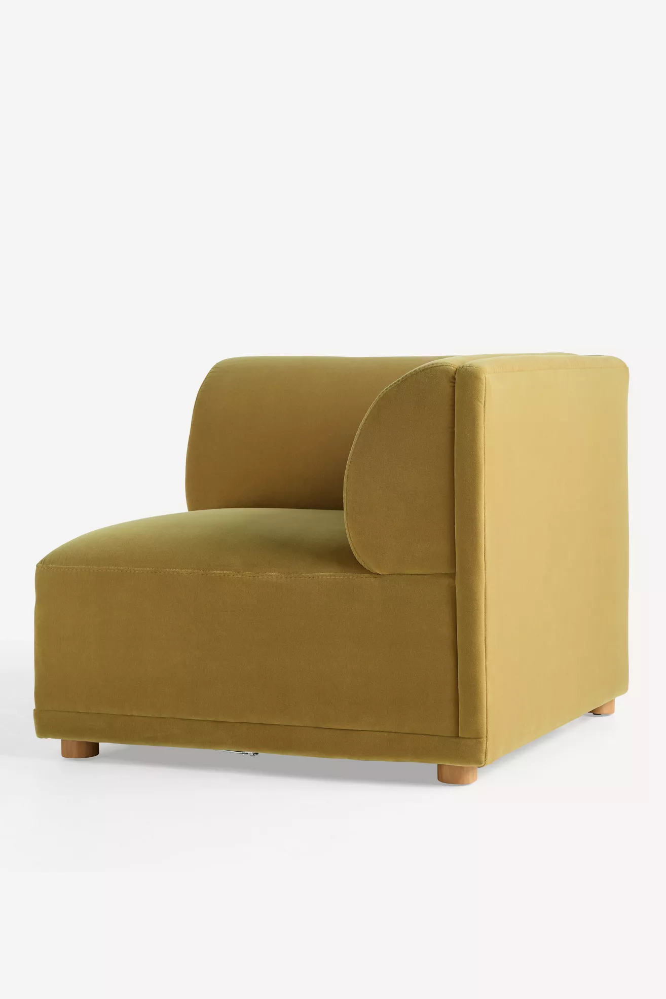 Side perspective of mustard velvet chair showing cylindrical back cushion