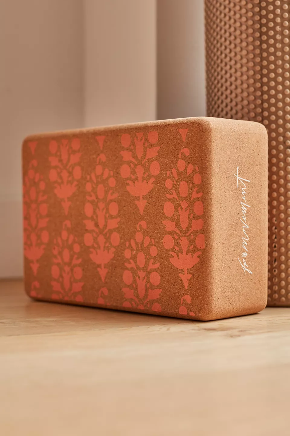 A brown yoga block with a pink design