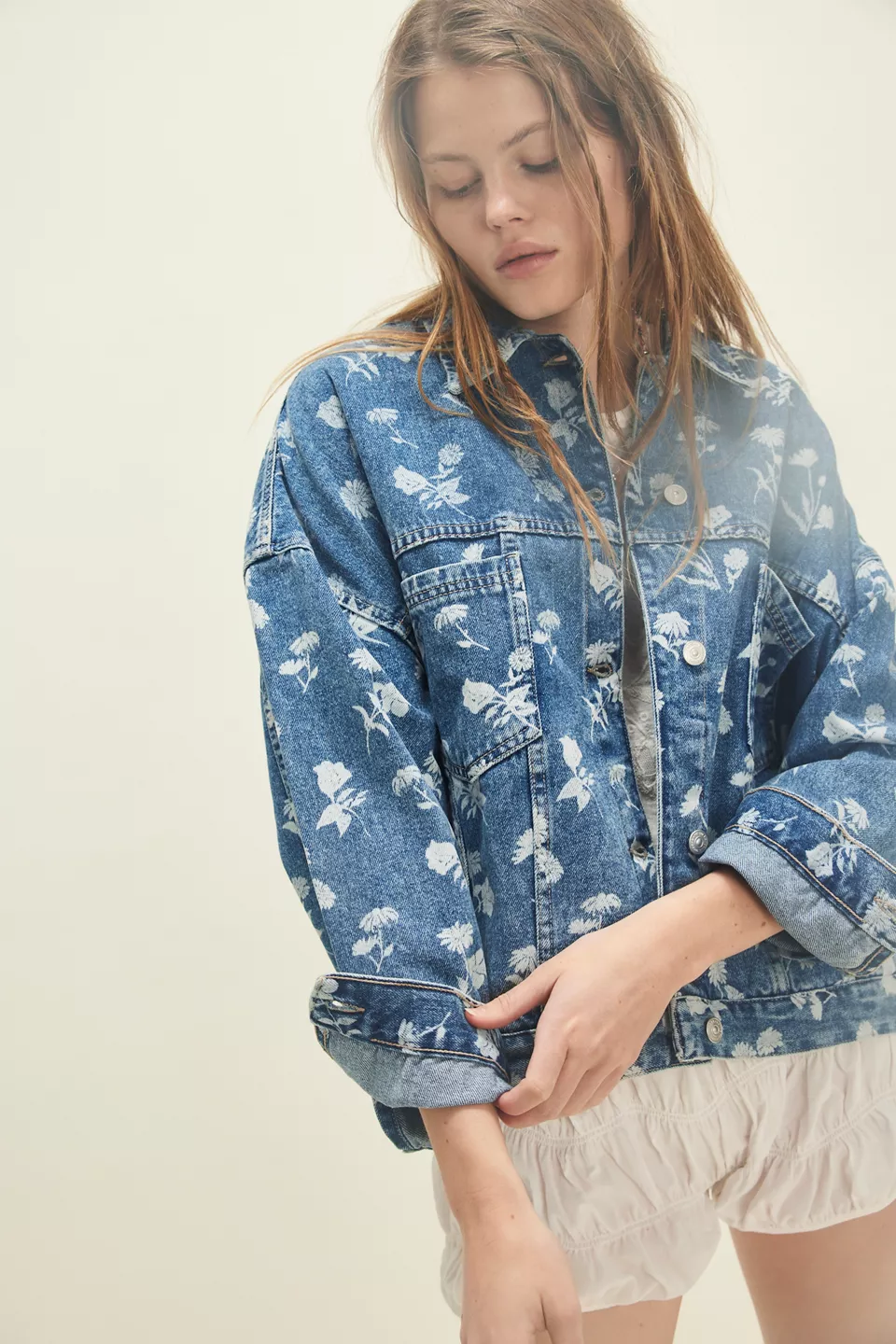 A woman wearing a denim jacket with white flowers on it