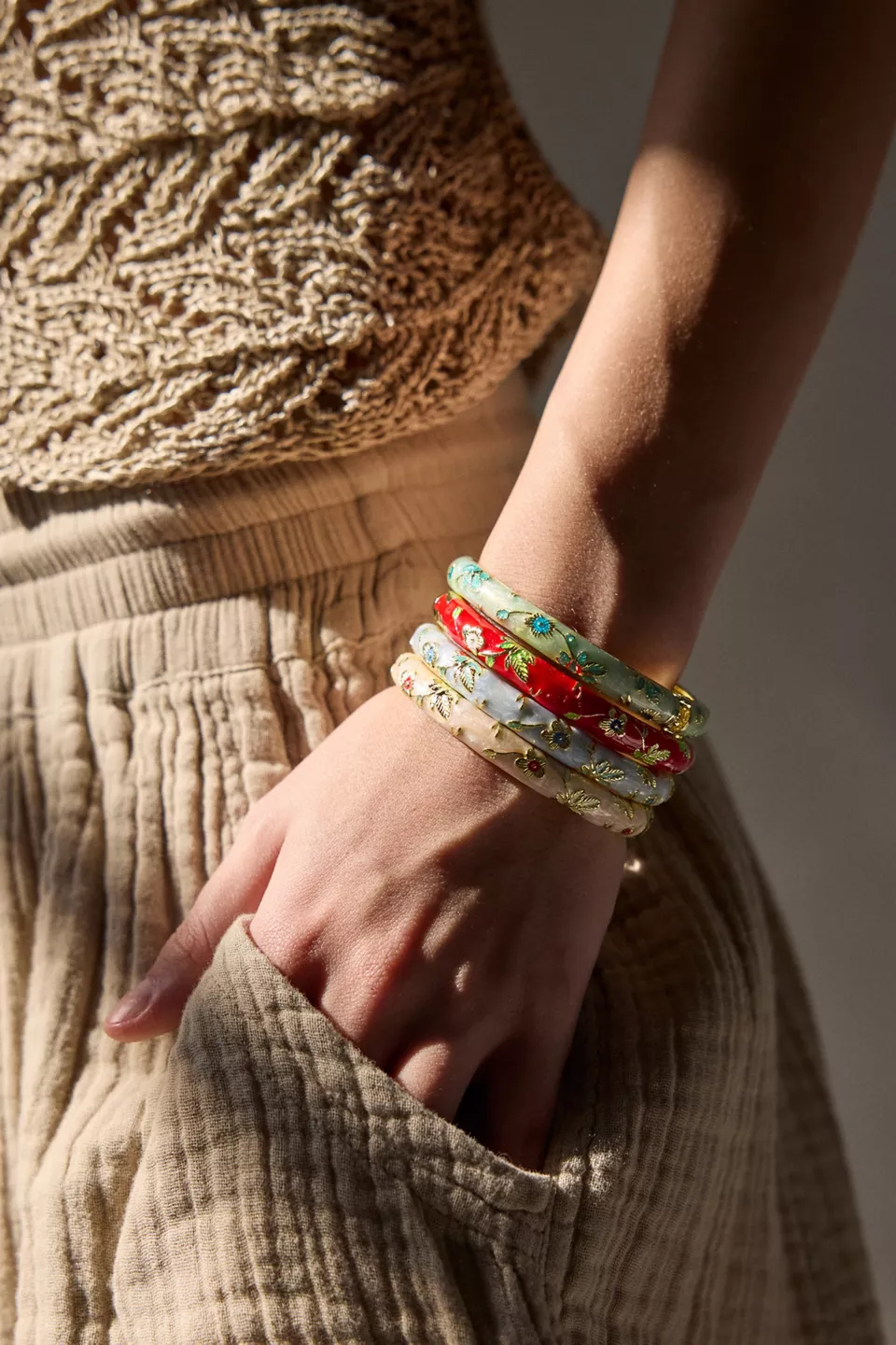 A person wearing four bangle bracelets