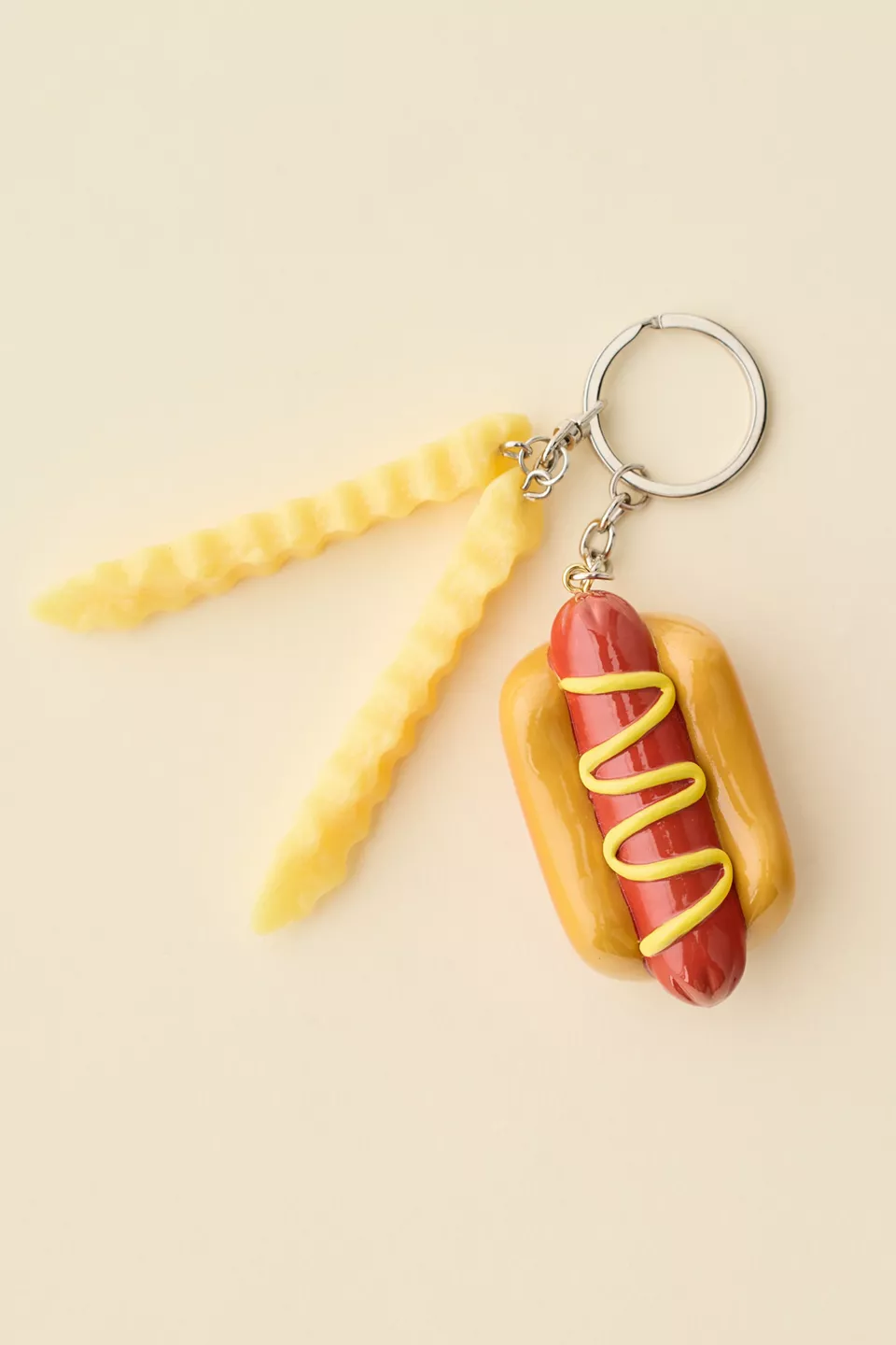 A keychain with a small hot dog shaped bottle opener and two fake French fries