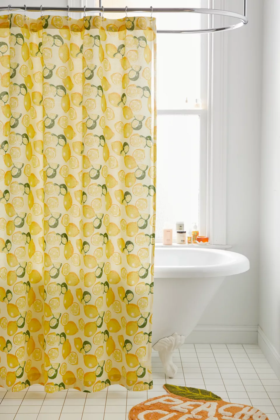 A lemon and lime patterned shower curtain hanging in front of a bathtub