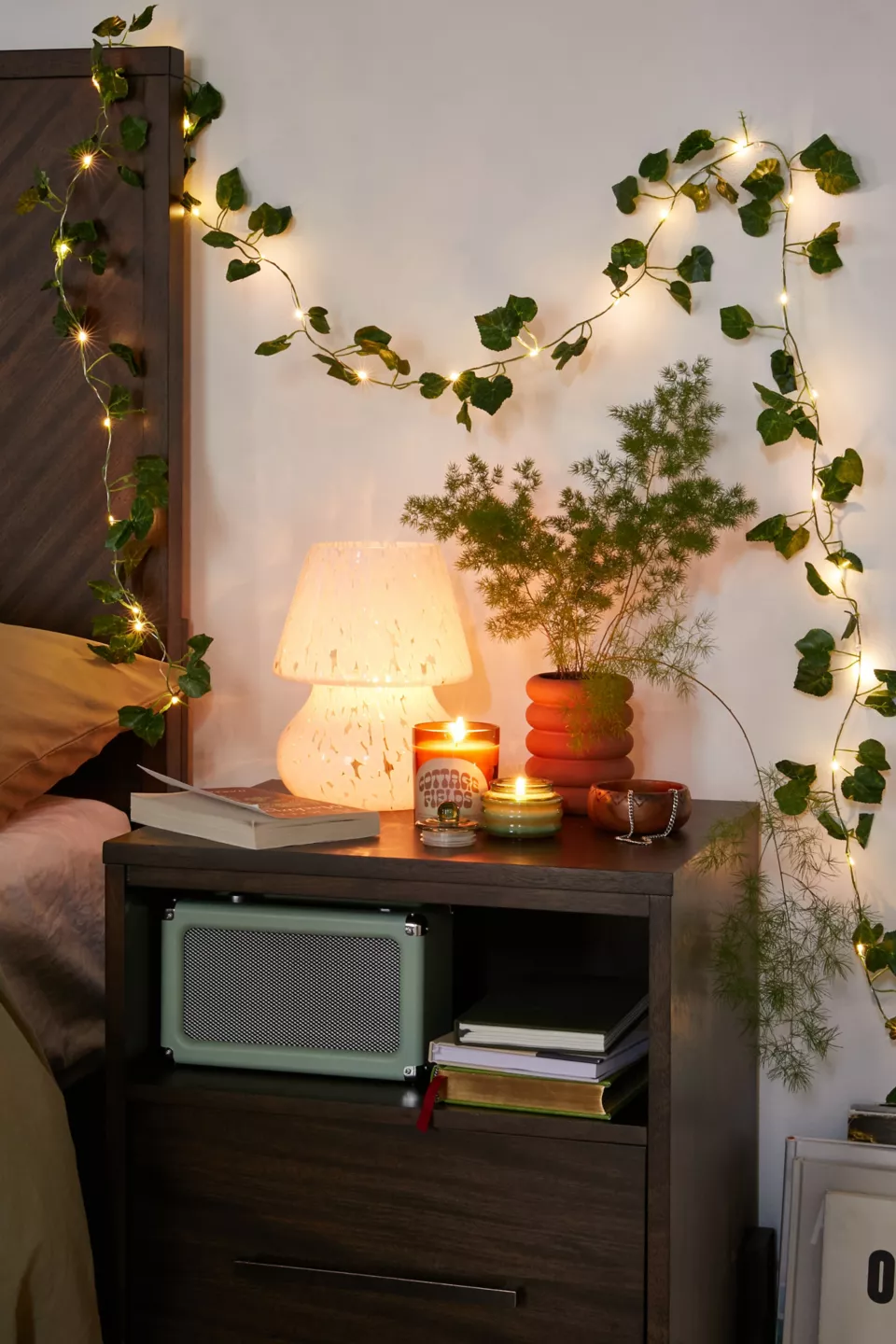 One vine of green leaves fairy lights is hung on the wall above a bed