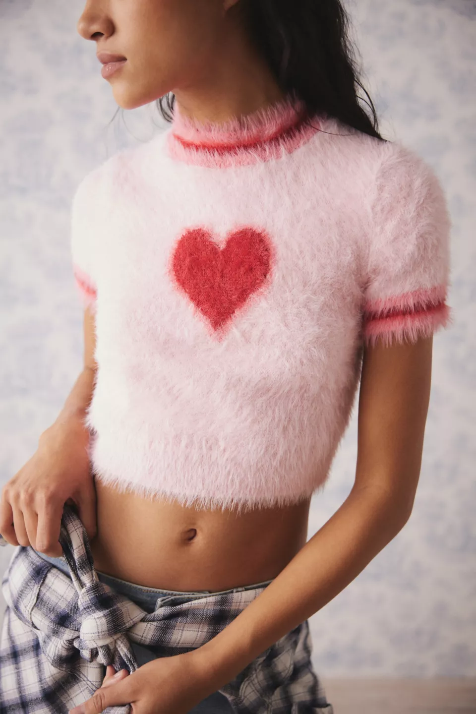 Woman in fuzzy pink sweater with red heart on it.