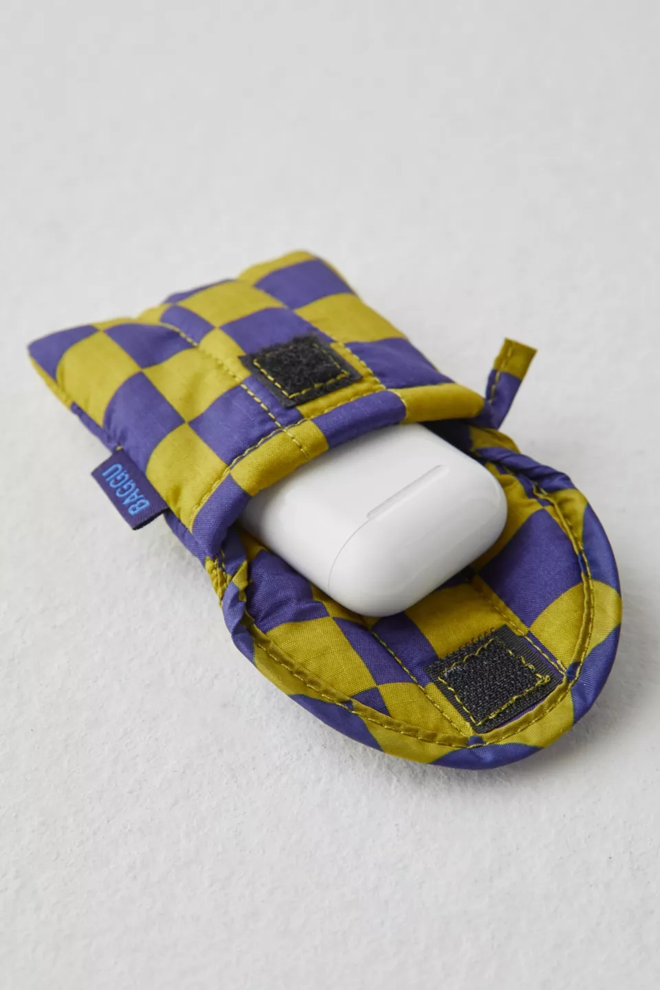 A green and purple checkered AirPods bag with AirPods inside it