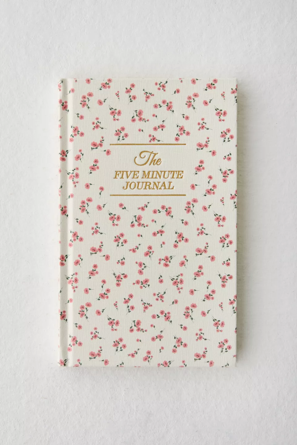 A white journal covered in pink flowers with gold text